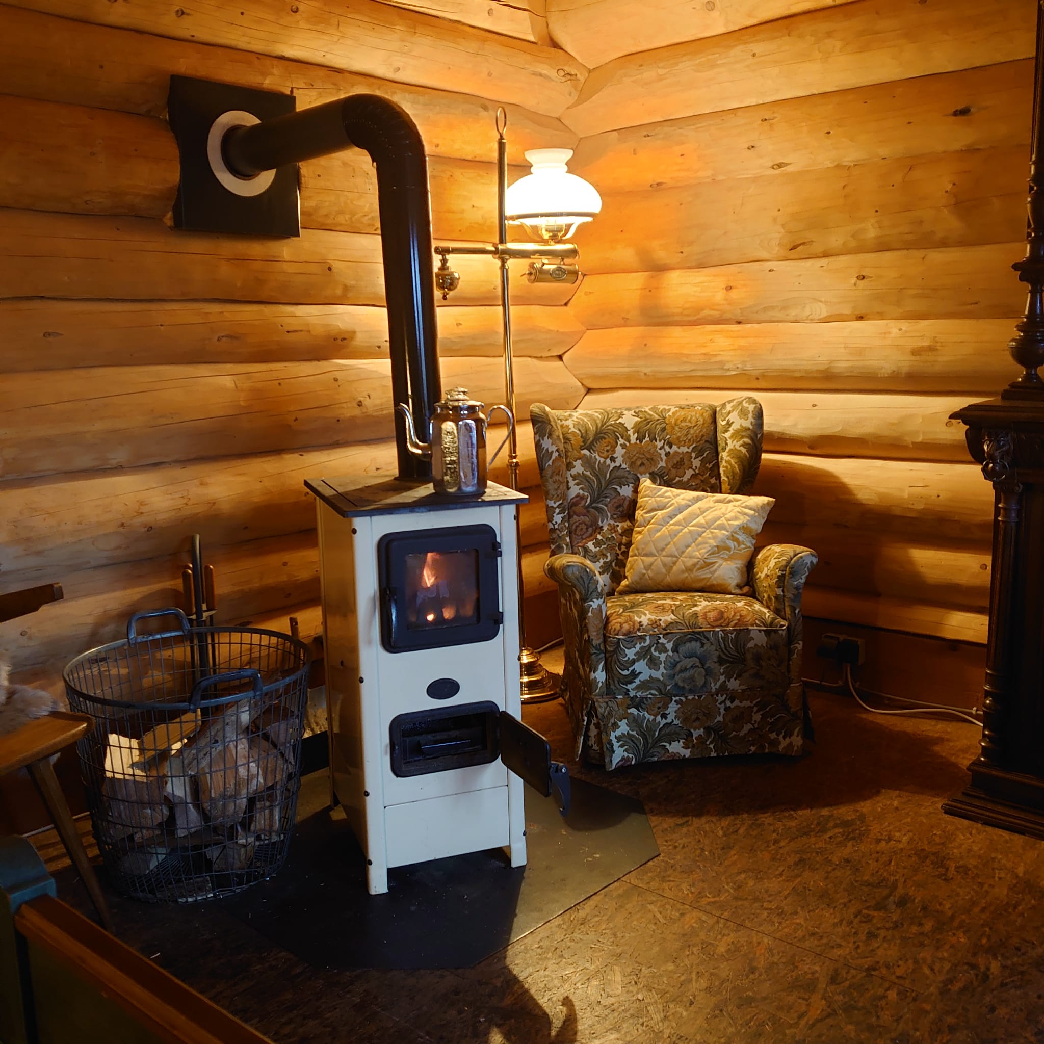 Gemütlicher Ohrensessel mit antiker Lampe und Ofen